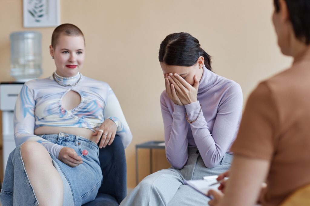 Sad young people discussing problems in group together with psychologist