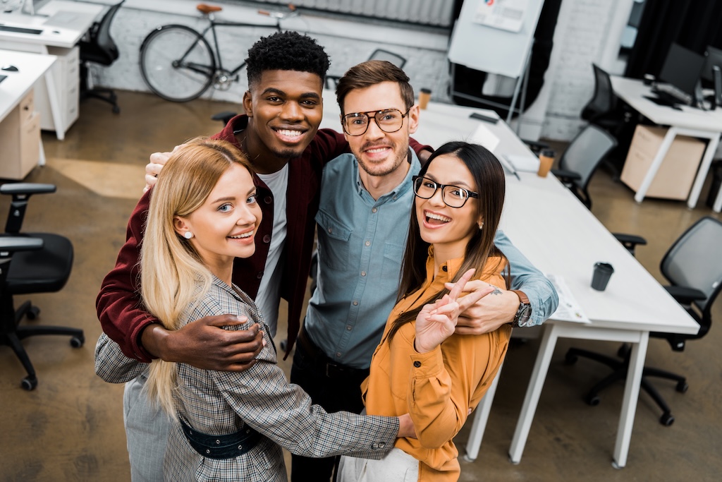 high angle view of multiethnic happy business colleagues looking at camera in office
