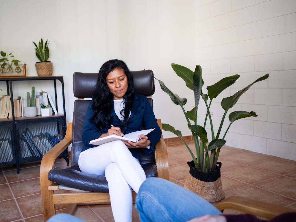 A psychologist in her thirties is engaged in a session with a patient