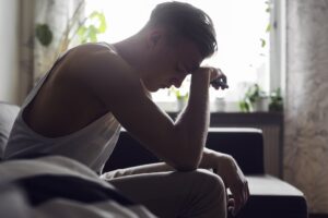 Pensive young man sitting on sofa