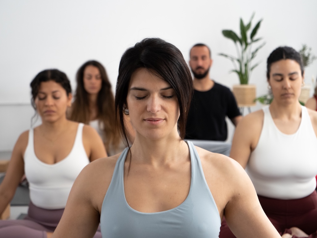 Close-up portrait of female yoga instructor with eyes closed while meditating in class