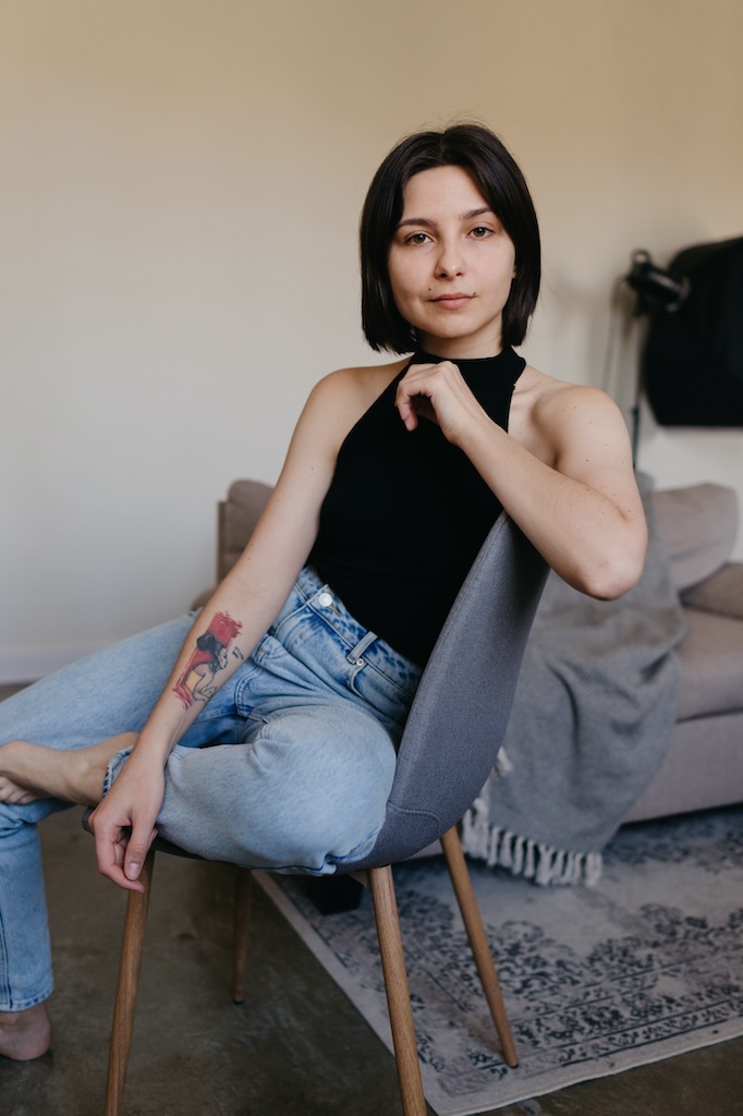 Young person sitting in a chair, looking at camera.