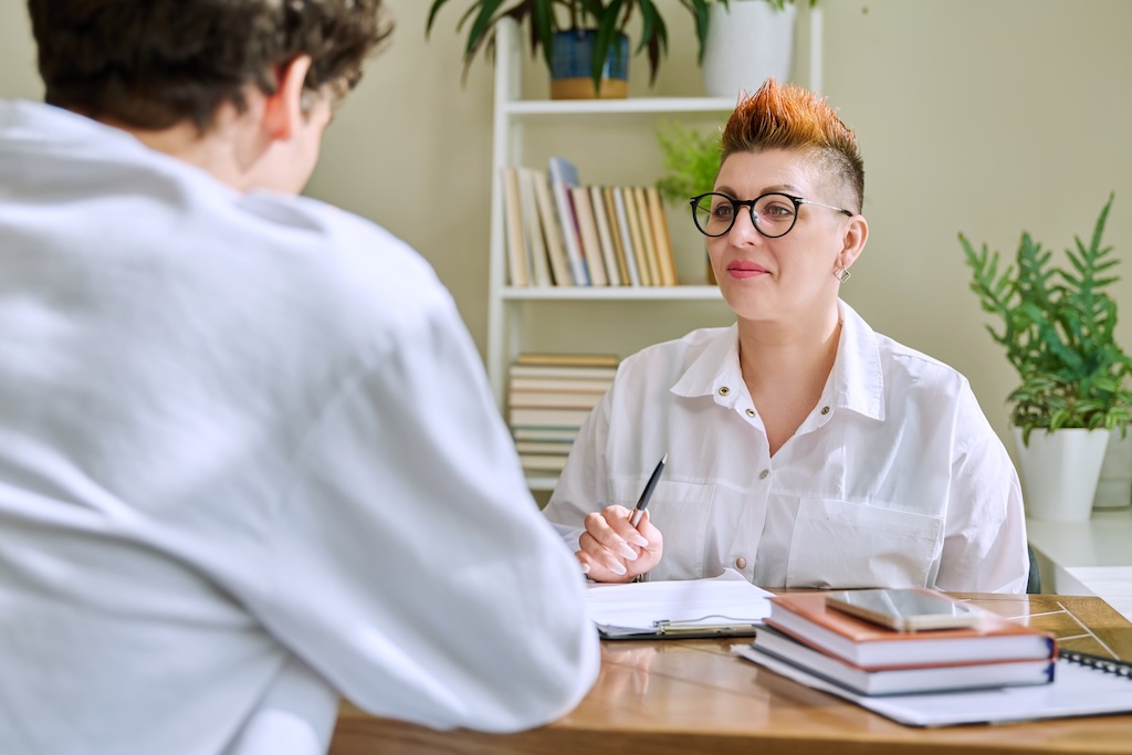 Female professional psychologist mental therapist working with young person providing case management services in office