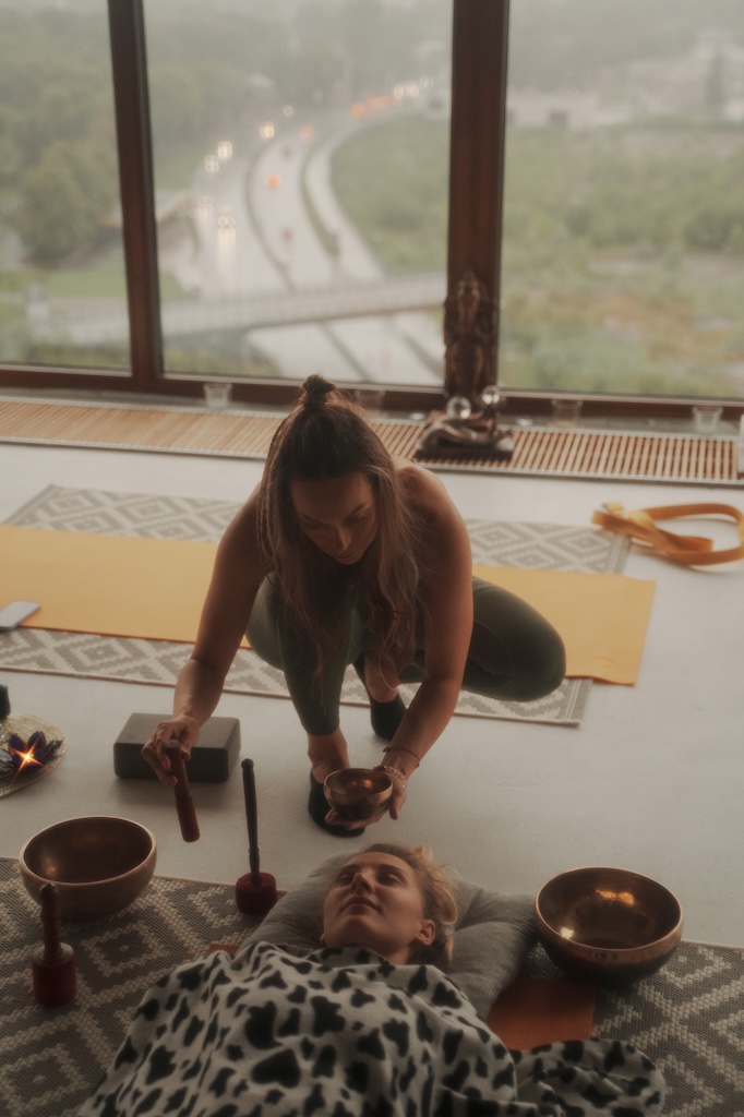 A peaceful scene of individuals practicing spiritual activities and yoga using a singing Tibetan bowl, surrounded by a calming atmosphere