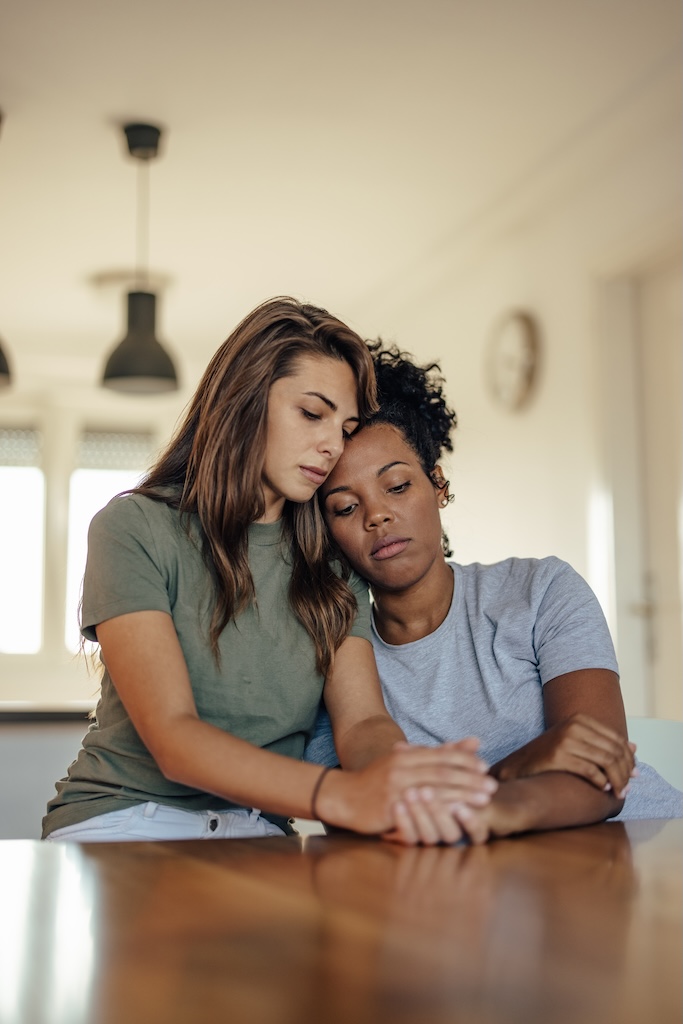 Anxious woman, leaning on her friend, while talking