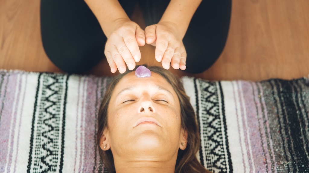 Therapist giving Reiki treatment to woman with stones in the head