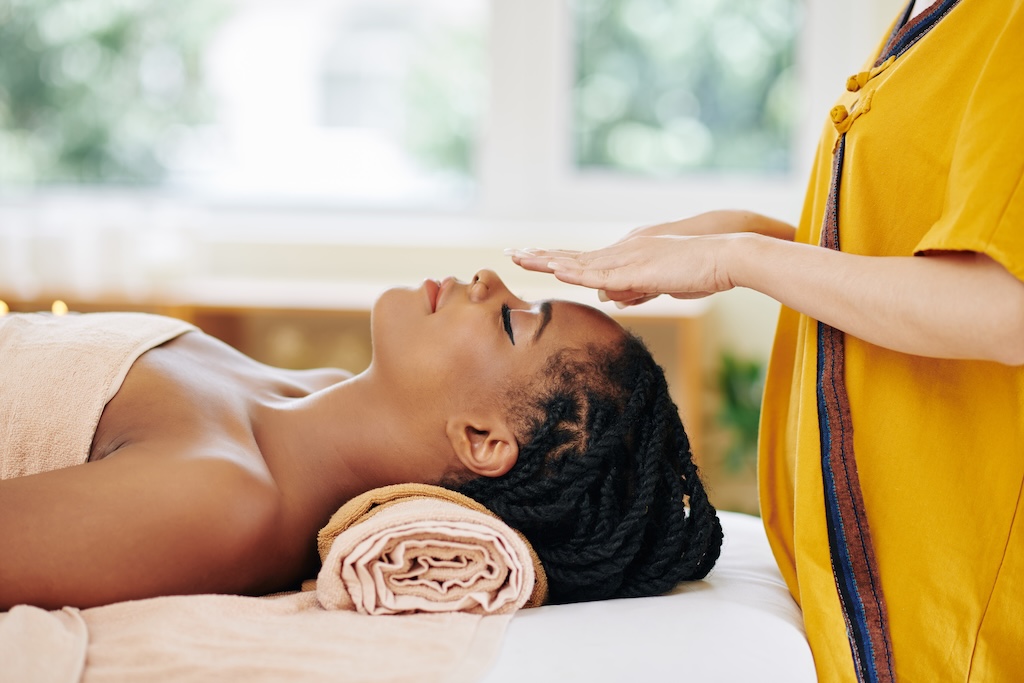 Attractive young woman getting reiki healing therapy in spa salon
