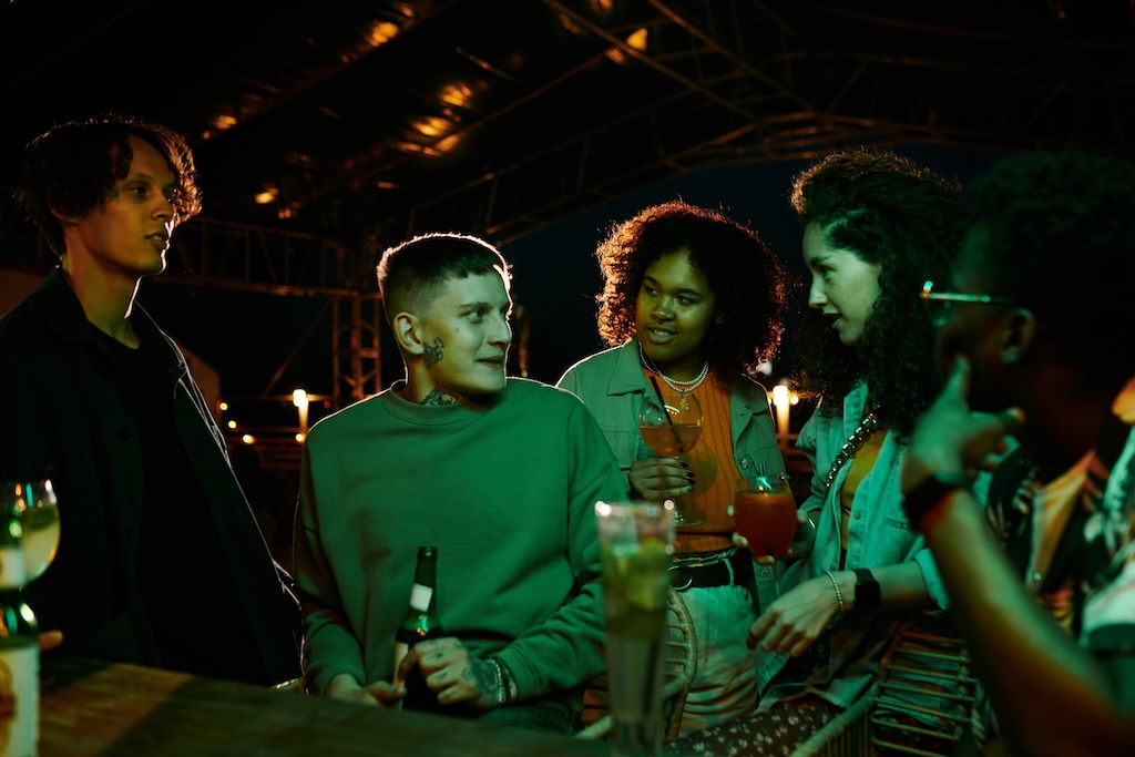 Youthful intercultural individuals with cocktails while at party night at a club