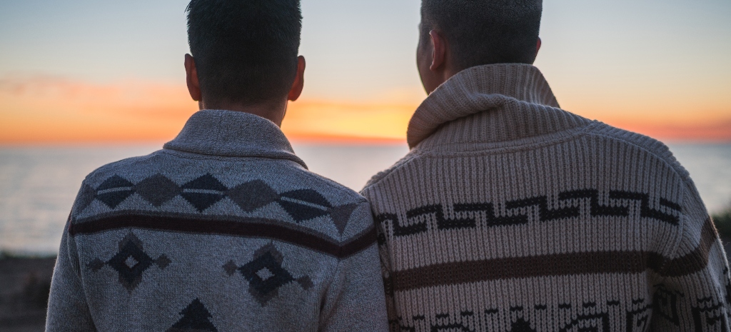 LGBTQIA couple looking out at sunset on the beach, representing healing from addiction and substance use patterns