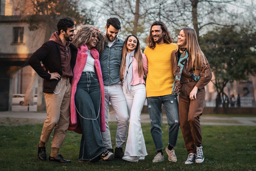 multiethnic group of positive young people walking arm on shoulders in the park - diversity and inclusion lifestyle concept