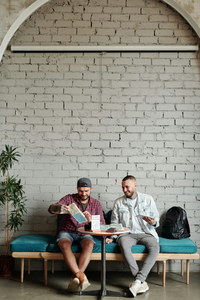Two men sitting together on a bench in a modern space, representing supportive LGBTQ+ community in addiction treatment in San Diego