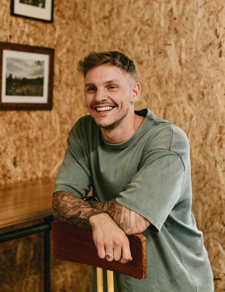 Smiling person leaning on a chair in a warm, welcoming setting, representing an approachable and supportive alcohol rehab team in San Diego.
