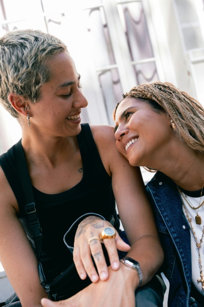 Two women sitting closely together and smiling, representing community-centered, affirming support at an LGBTQIA+-owned alcohol rehab in San Diego.
