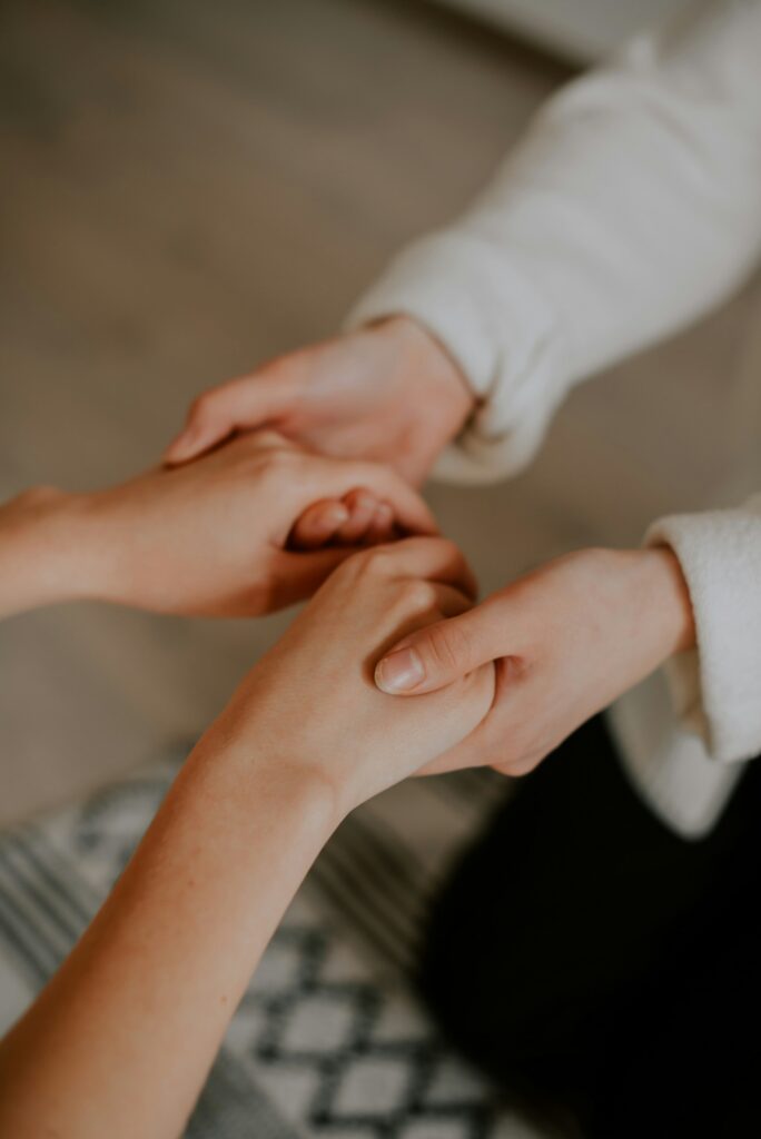 Close-up of two people holding hands during a supportive meeting at an LGBTQ+ addiction treatment center in San Diego