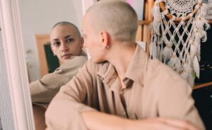Close-up of a person looking at their reflection in a mirror, conveying a thoughtful, introspective moment related to identity and self-perception.