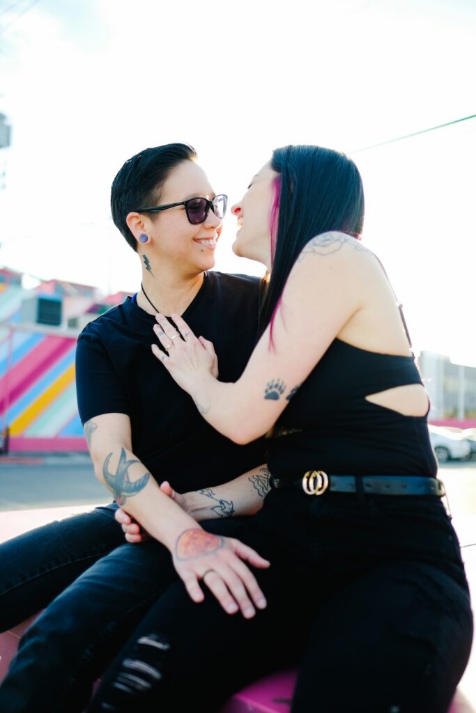 Two individuals sitting closely together, smiling and laughing, representing connection, support, and community within LGBTQIA+-affirming mental health and trauma treatment programs (IOP/PHP)