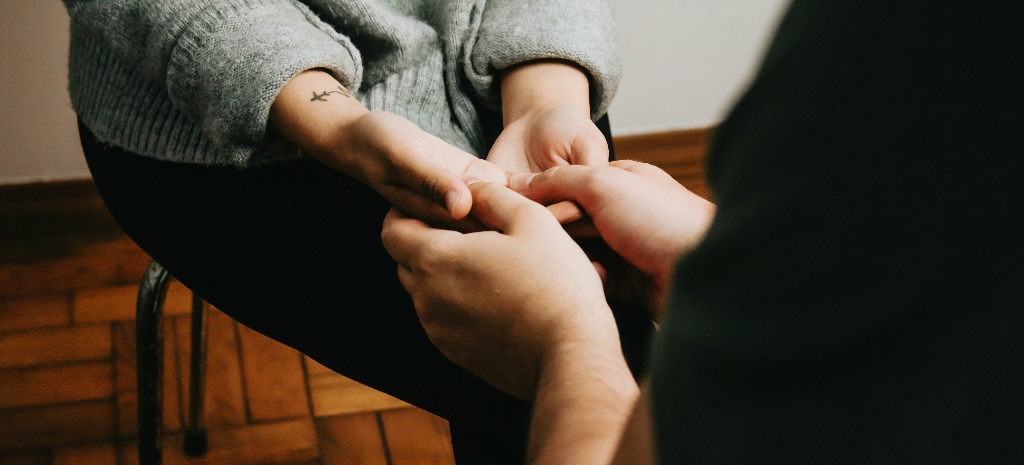Two people sit facing each other, hands gently held together, representing connection, healing, and the possibility of building healthy relationships after a trauma bond.