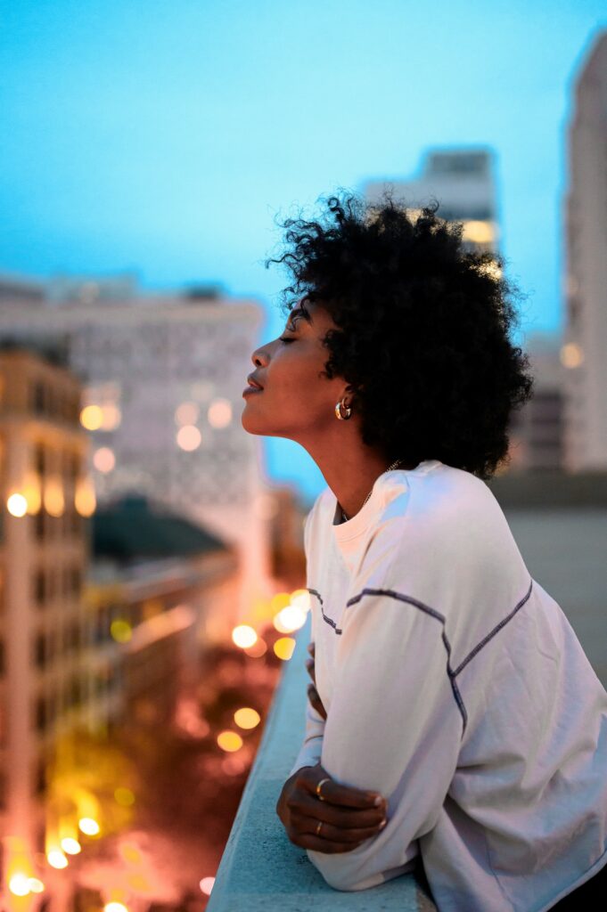 Person standing on a balcony overlooking the city at dusk, reflecting a moment of calm and openness to support for cocaine addiction recovery
