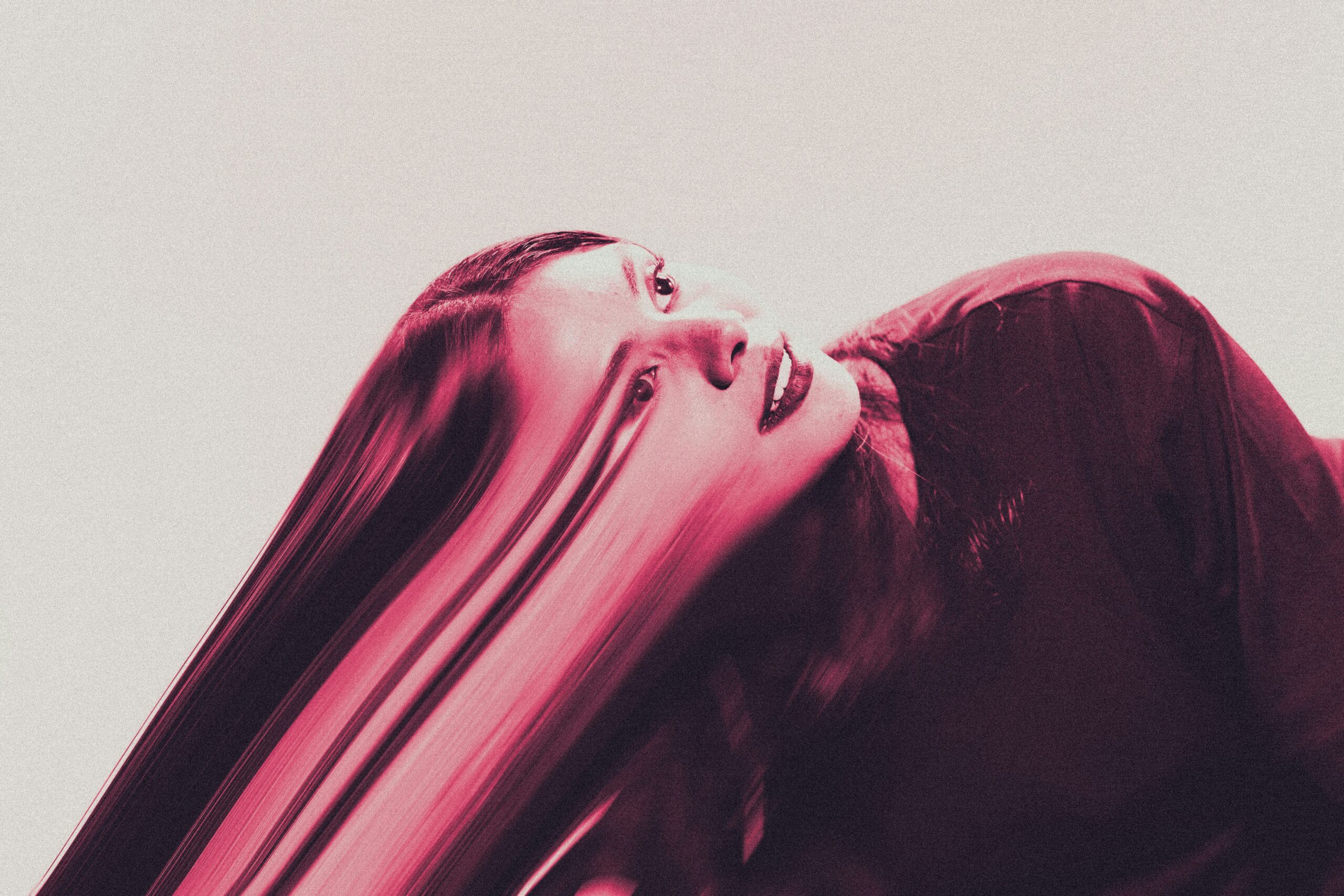 Person with long hair against a neutral background, with a visual distortion effect across their face and hair, conveying emotional discomfort and disconnection.