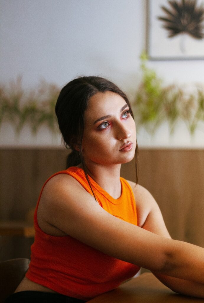 Person sitting thoughtfully in a warm-toned space representing reflection, emotional support, and seeking ADHD treatment.