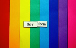 They/them pronoun tiles displayed on a rainbow background representing gender identity, self-expression, and LGBTQIA+ inclusion.