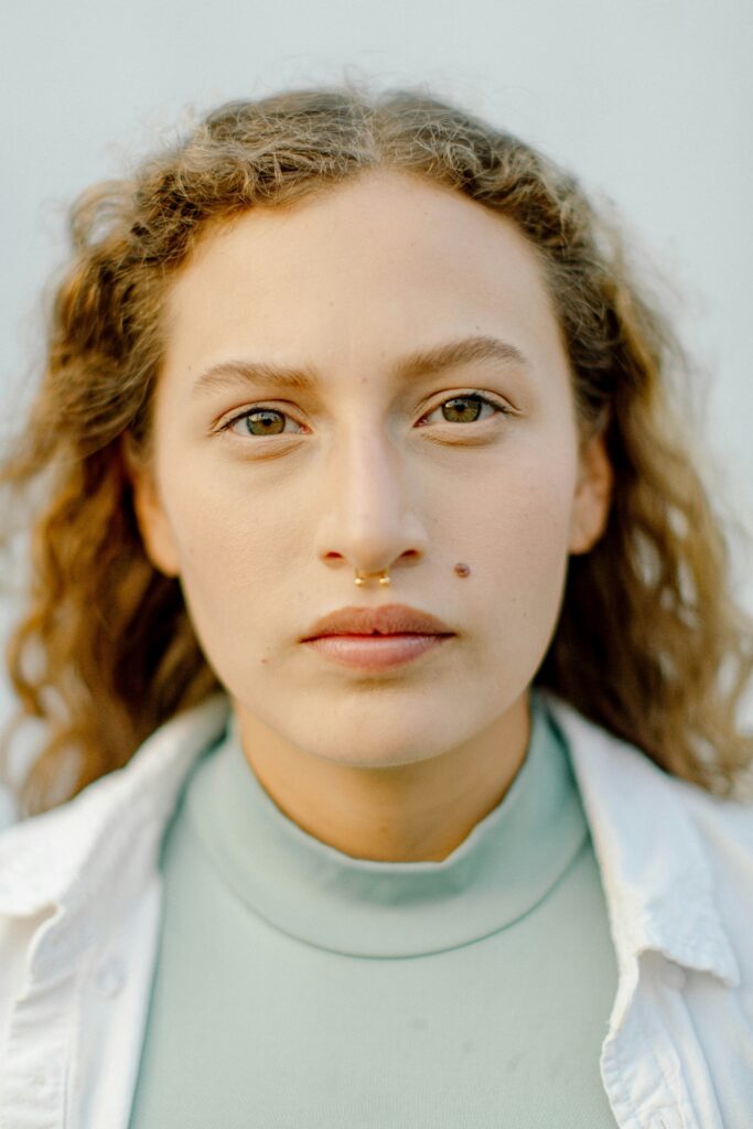 Close-up portrait of a person with curly hair and a septum piercing, representing neurodivergent and LGBTQIA+ affirming mental health treatment.