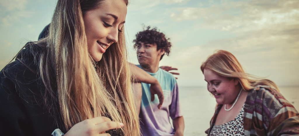 Group of young adults spending time together outdoors near the beach, reflecting themes of connection, support, and healing from isolation and depression.