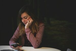 Young woman looking at her phone with a thoughtful expression, reflecting on a social interaction.