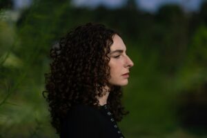 Person with curly hair in profile reflecting on compulsory heterosexuality and sexual identity.