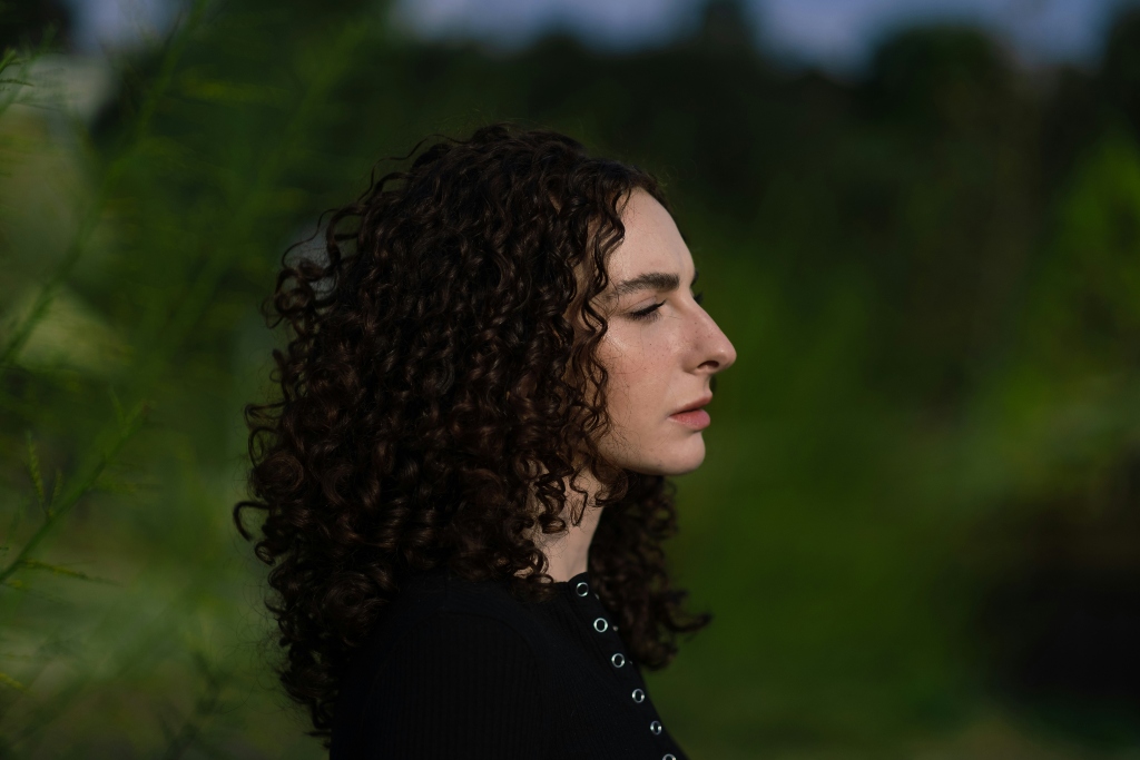 Person with curly hair in profile reflecting on compulsory heterosexuality and sexual identity.