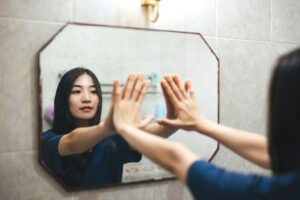 Person looking at their reflection in a mirror while exploring feelings of gender envy and identity.