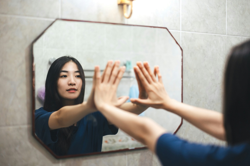 Person looking at their reflection in a mirror while exploring feelings of gender envy and identity.