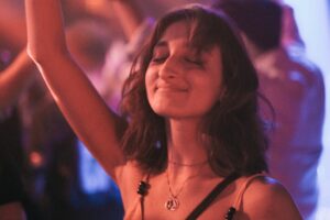 Person smiling with eyes closed while dancing, representing gender euphoria and the joy of authentic self-expression.
