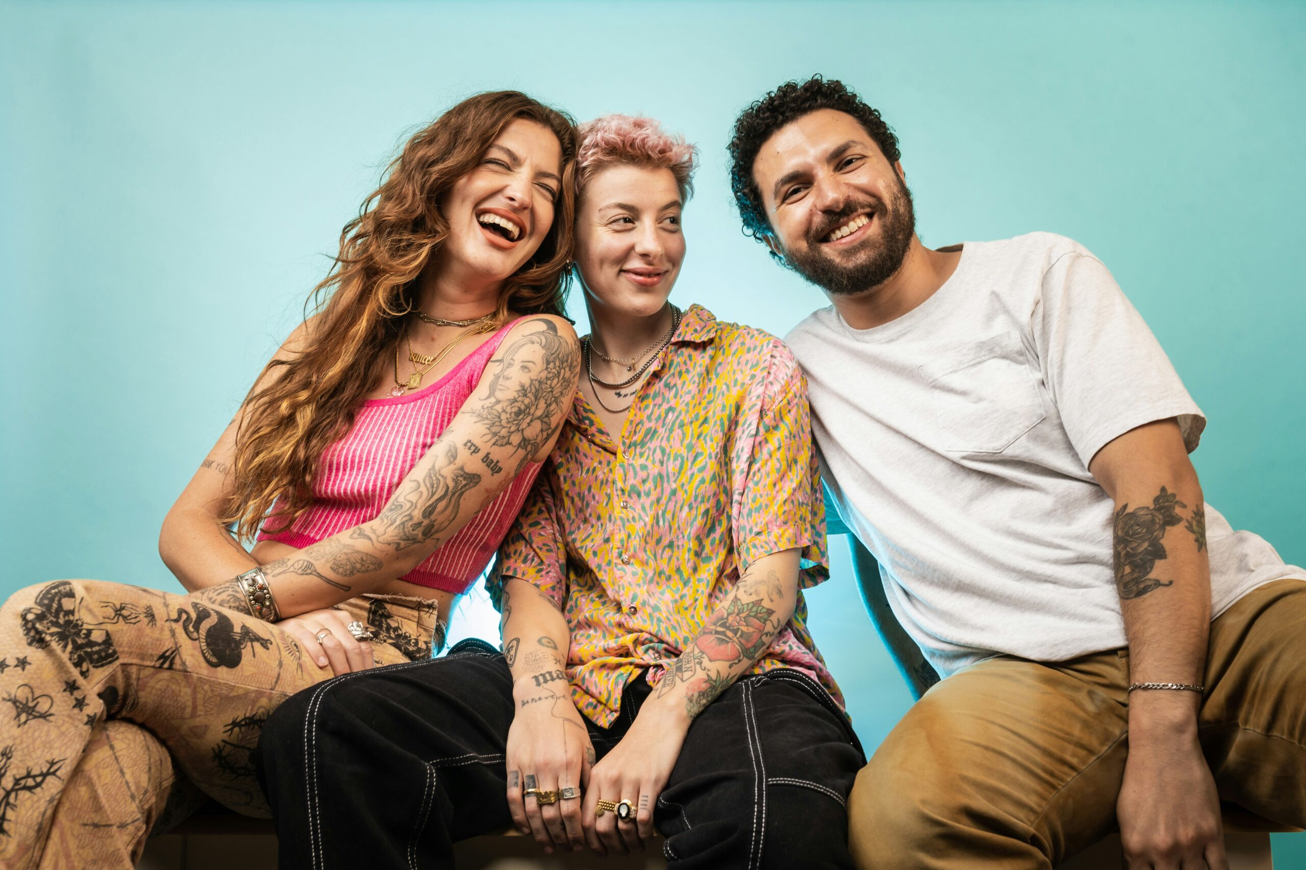 Three friends sitting closely together and smiling, illustrating connection in queerplatonic relationships.